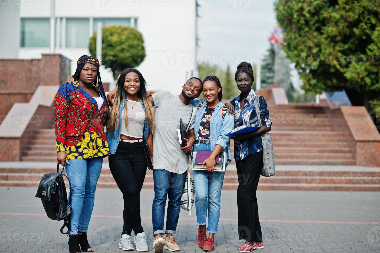 grupo de cinco estudiantes universitarios africanos que pasan tiempo juntos en el campus en el patio de la universidad. amigos negros afro estudiando. tema de la educación foto