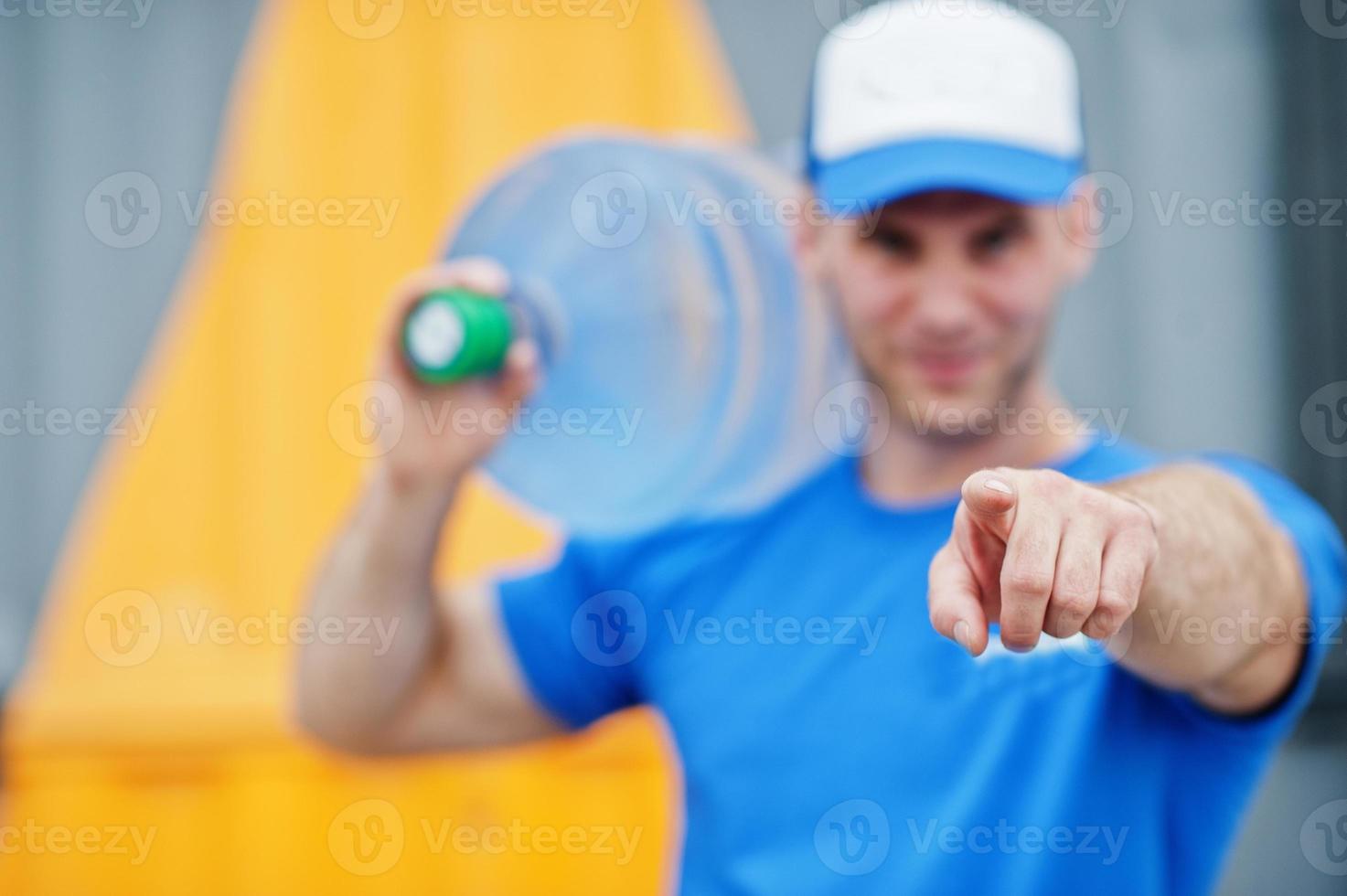 Delivery man carrying water bottle on shoulder and show finger to camera. photo