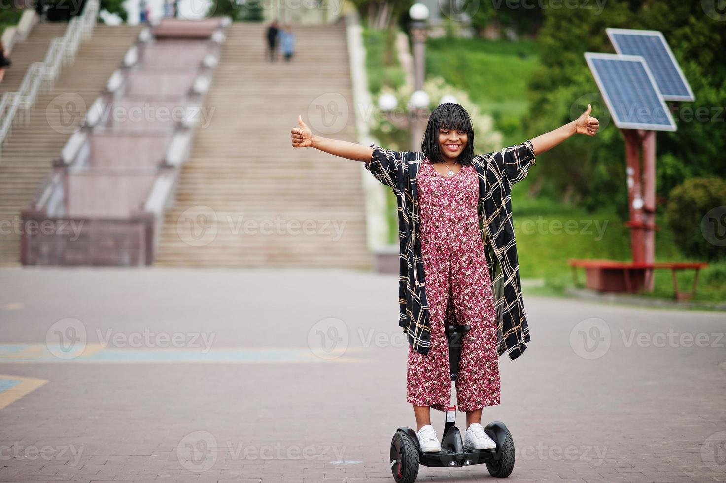Beautiful african american woman using segway or hoverboard. Black girl on dual wheel self balancing electrical scooter. photo