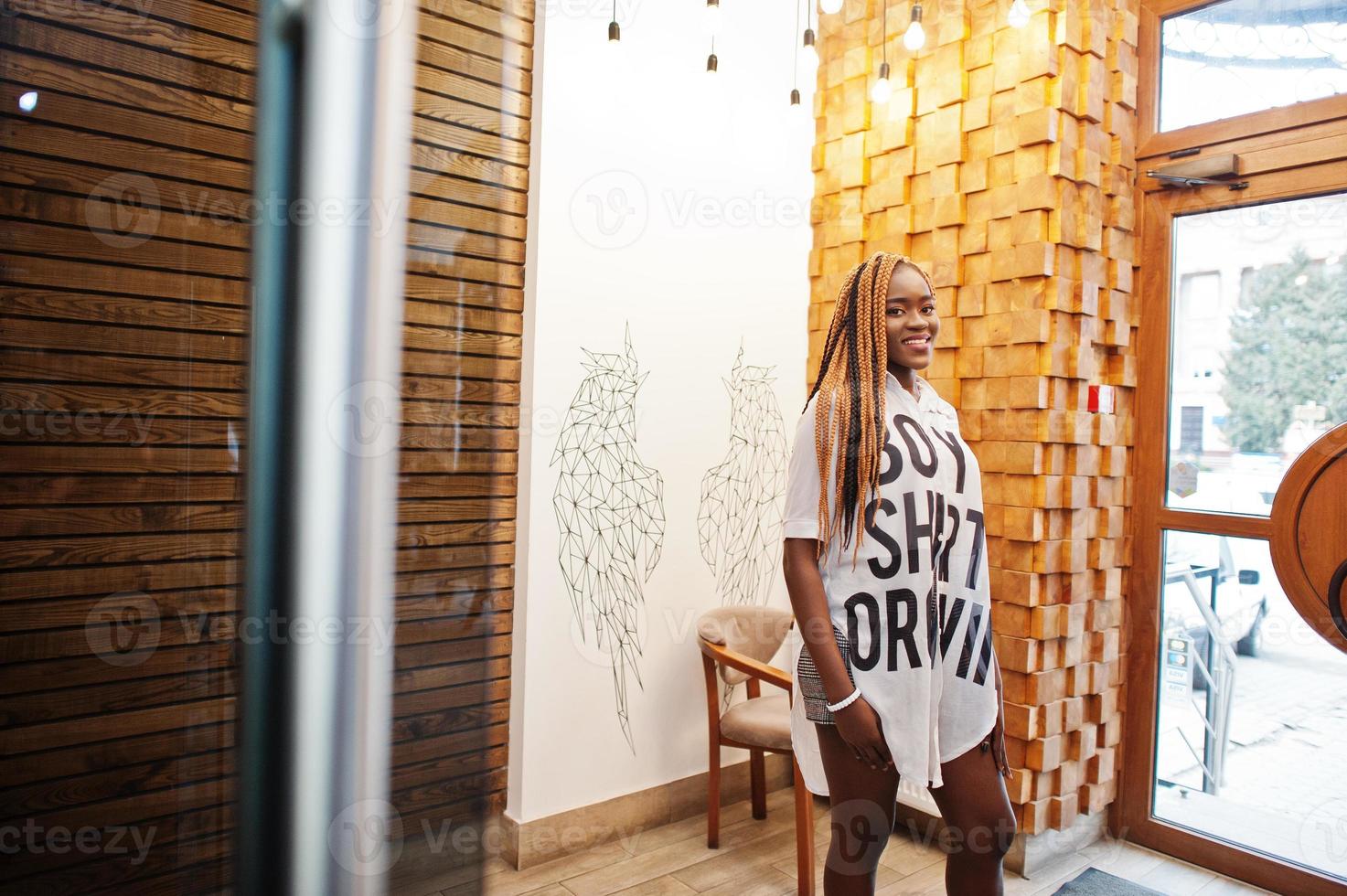 Beautiful african woman in stylish casual clothes posing against angel wings wall. photo