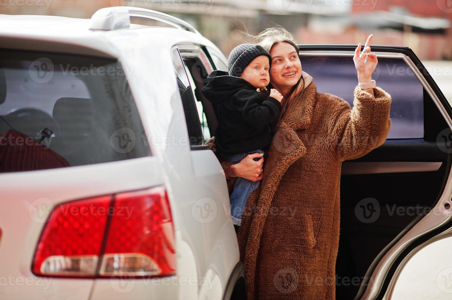 la joven madre y el niño se paran cerca de su auto todoterreno. concepto de conducción segura. foto