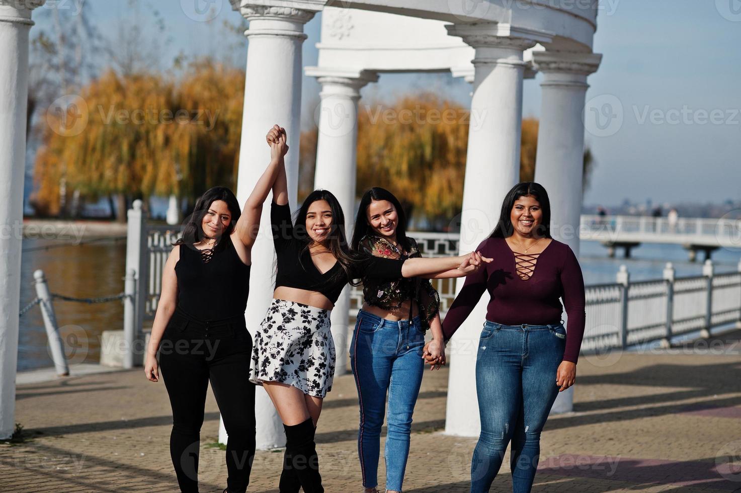 Group of four happy and pretty latino girls from Ecuador posed at street. photo