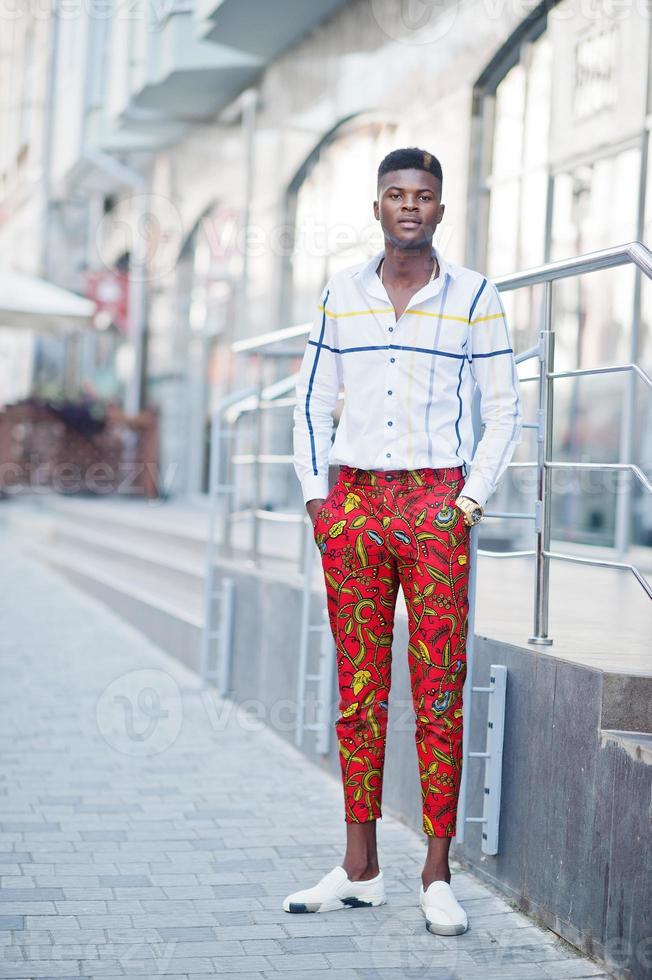 Portrait of handsome stylish african american model man in red throusers and white shirt. photo