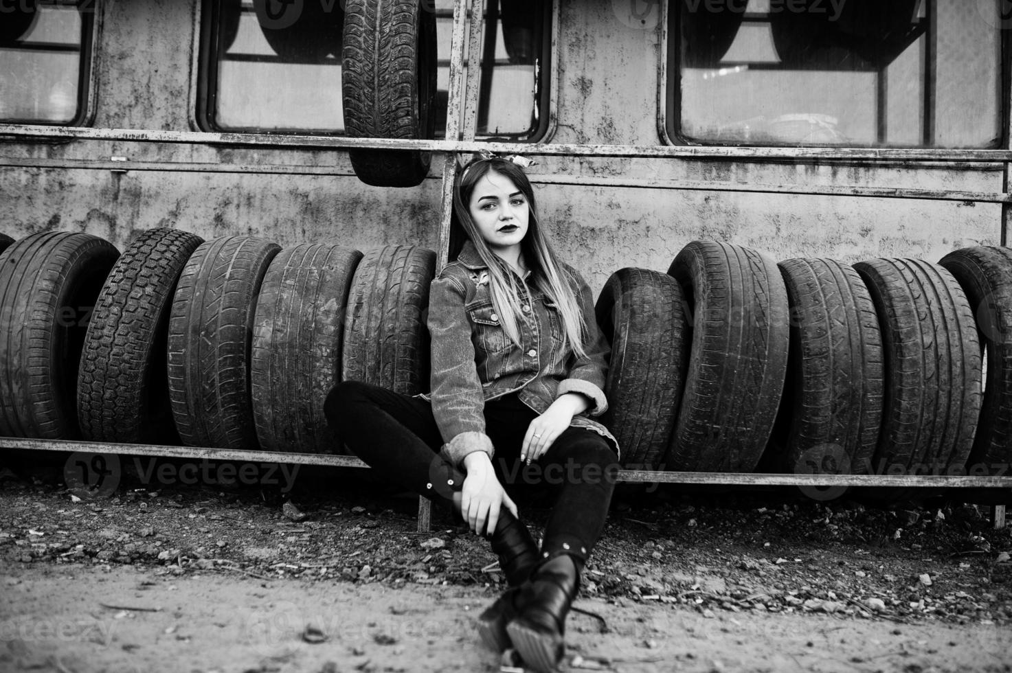 Young hipster girl in jeans jacket and head scarf at tire fitting zone. photo