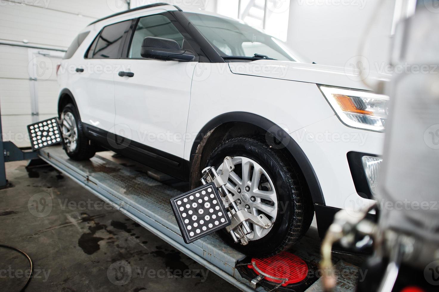 American SUV car on stand for wheels alignment camber check in workshop of service station. photo
