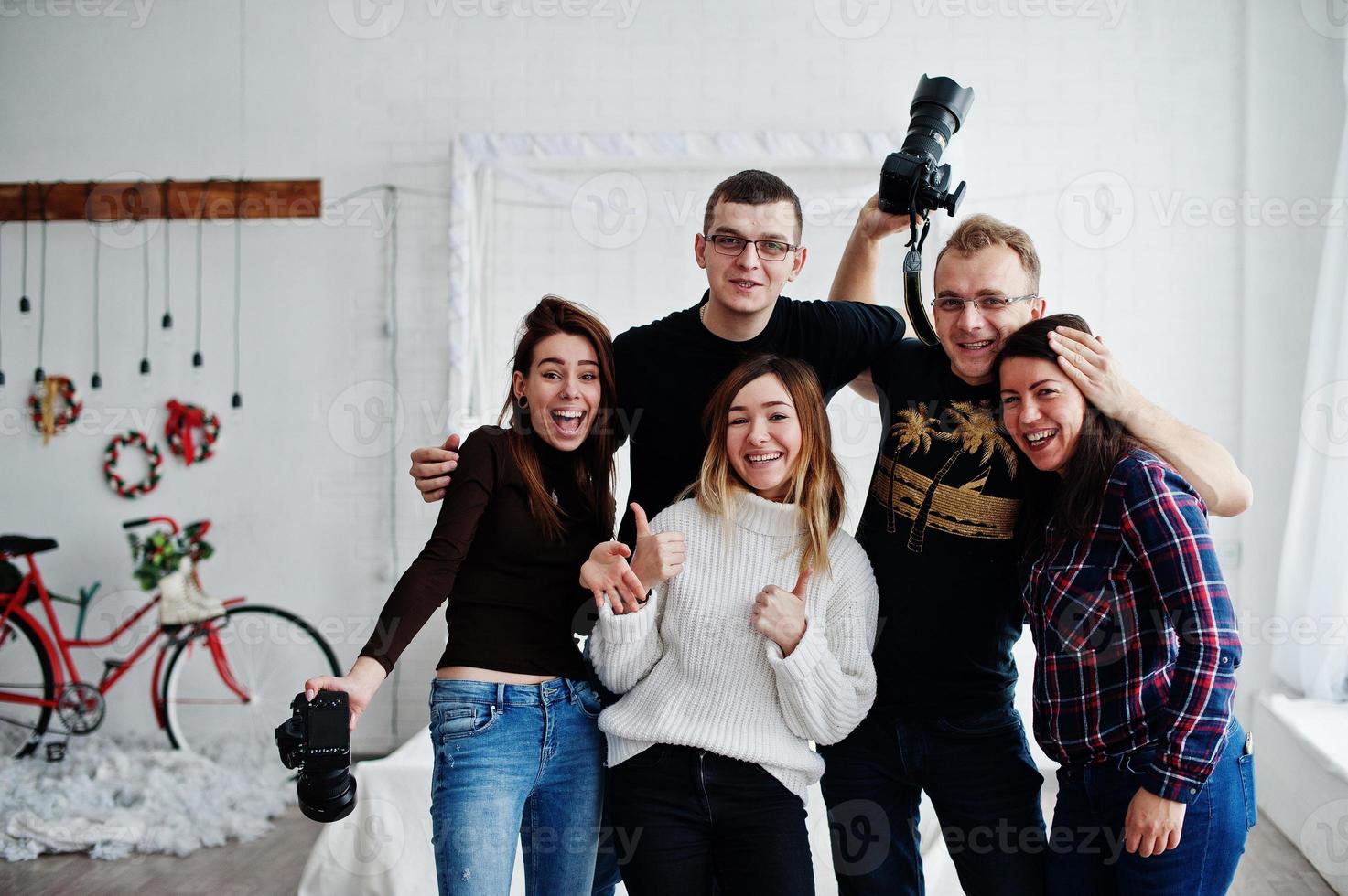 Group of five peoples, friends photographers and designers on studio shooting after hard work day. They happy and laughing. photo