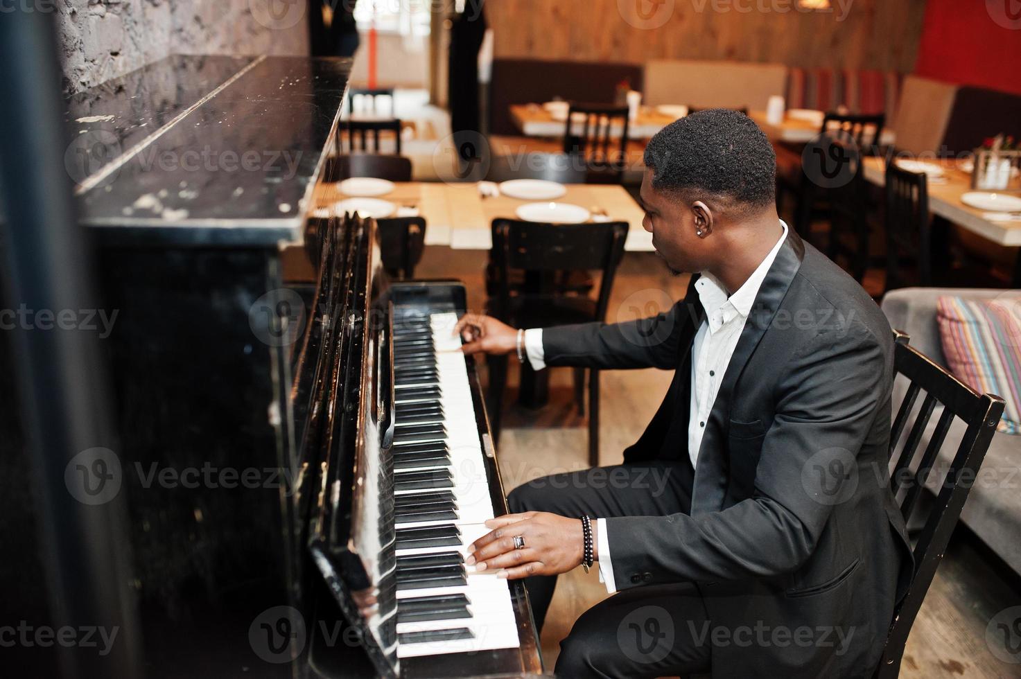 Strong powerful african american man in black suit play piano. photo