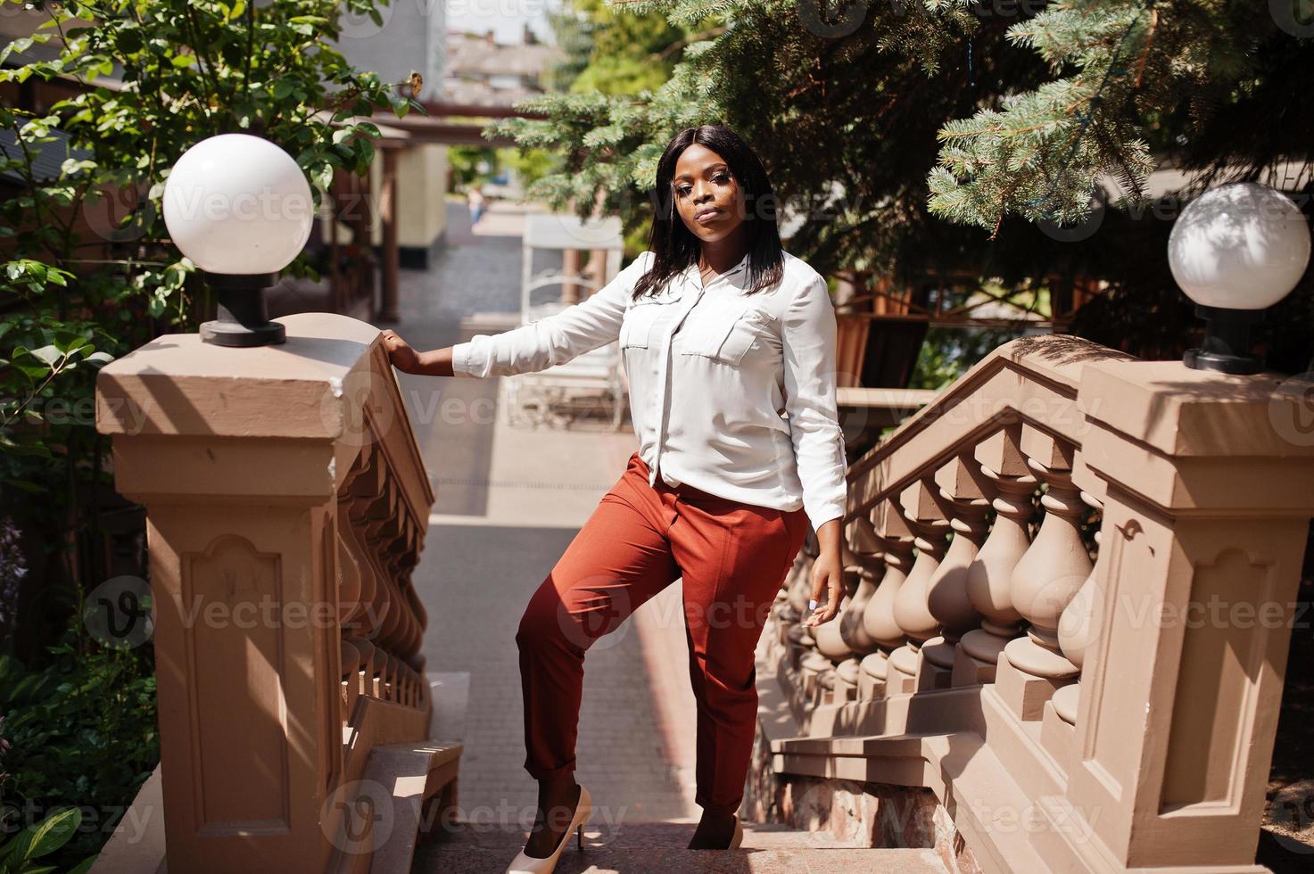 Formally dressed african american business woman in white blouse and red trousers. Successful dark skinned businesswoman. photo