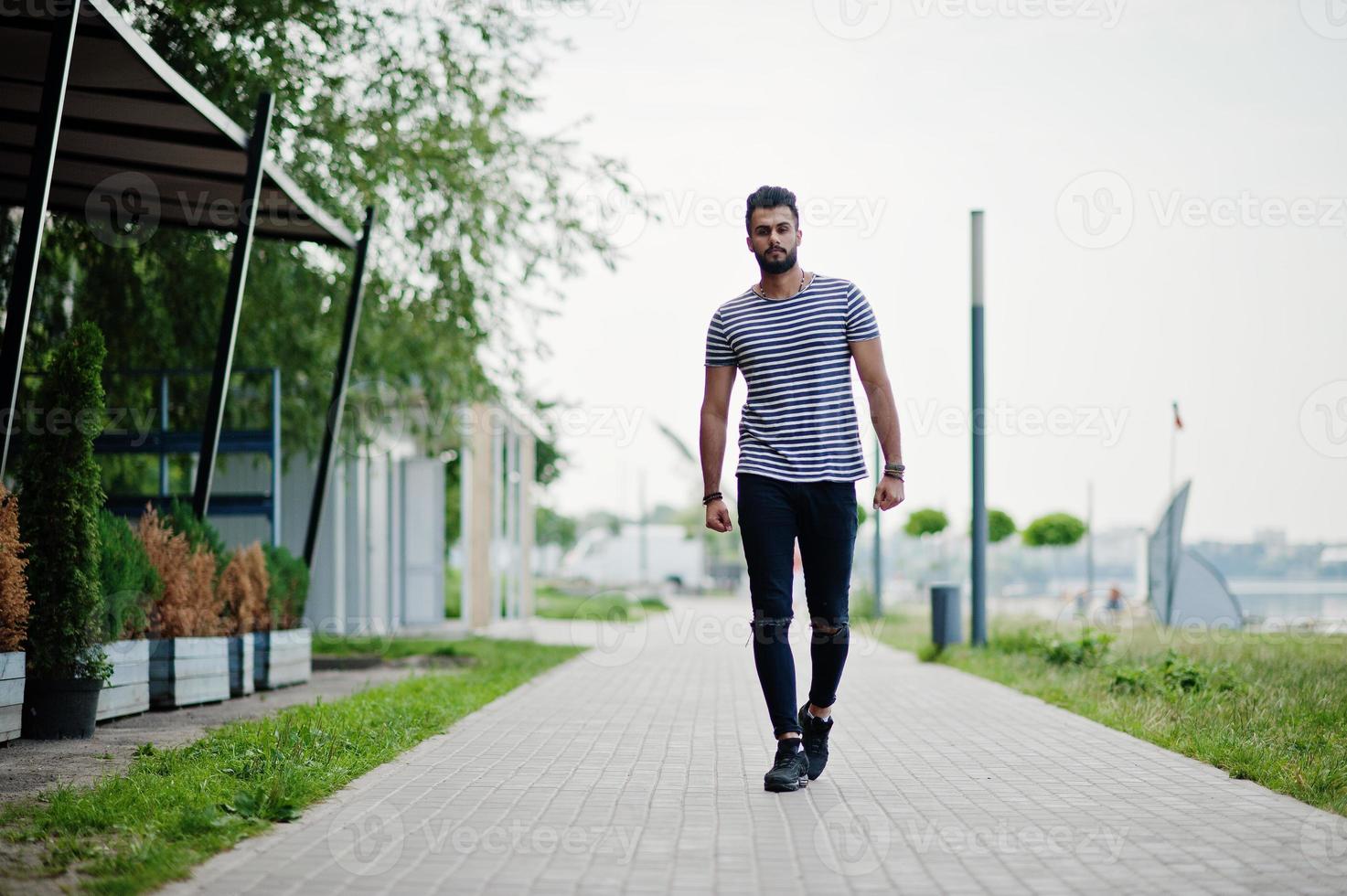 Handsome tall arabian beard man model at stripped shirt posed outdoor. Fashionable arab guy. photo
