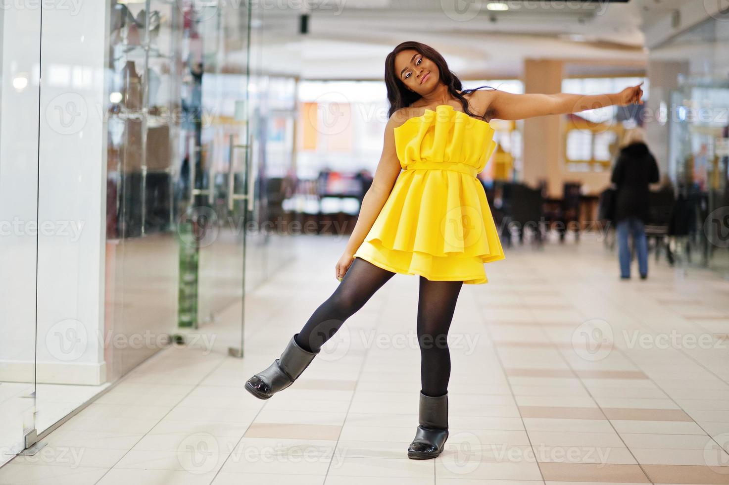 Stylish african american woman at yellow dreess posed at mall. photo