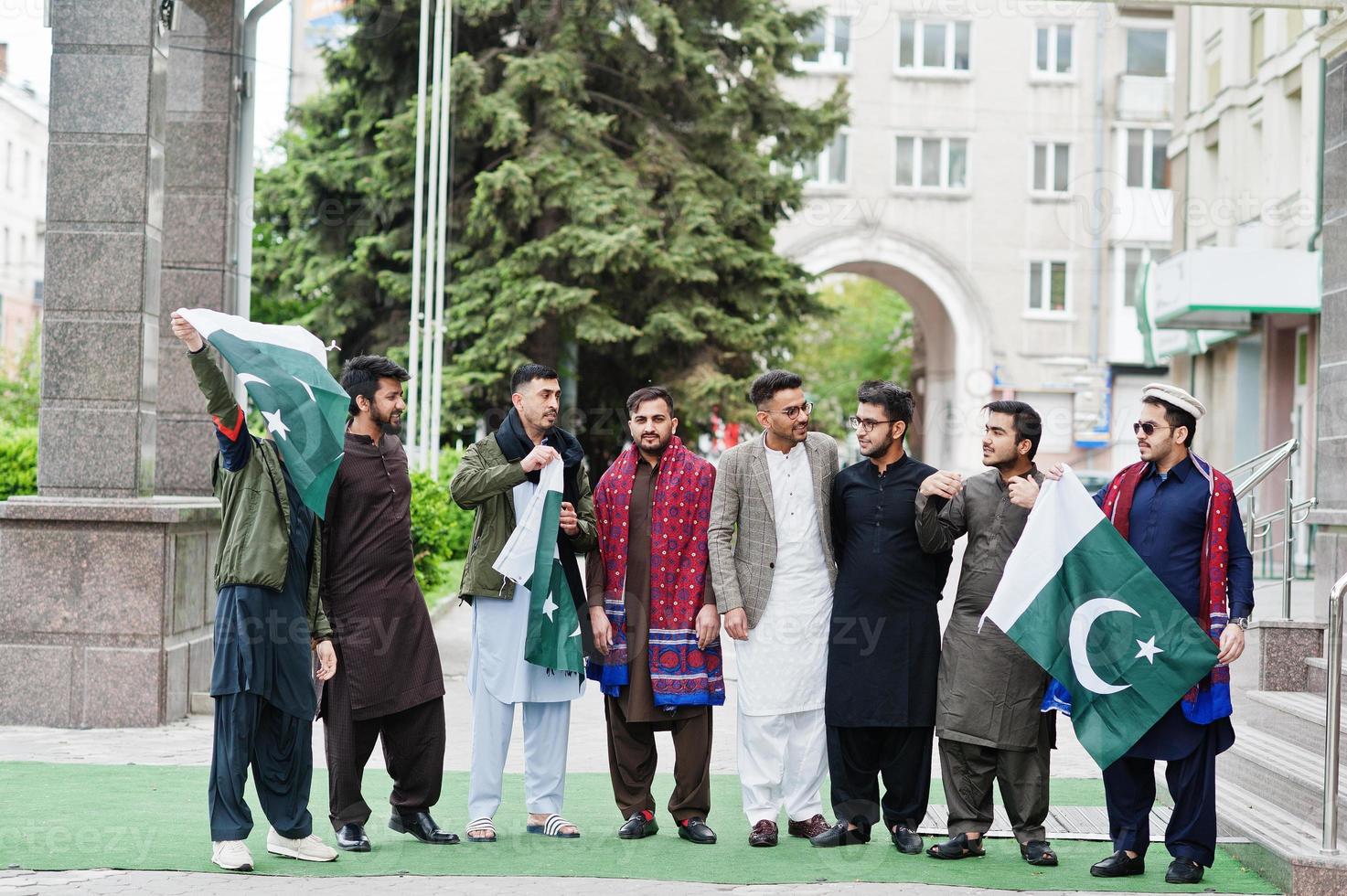 grupo de hombres paquistaníes vestidos con ropa tradicional salwar kameez o kurta con banderas de pakistán. foto