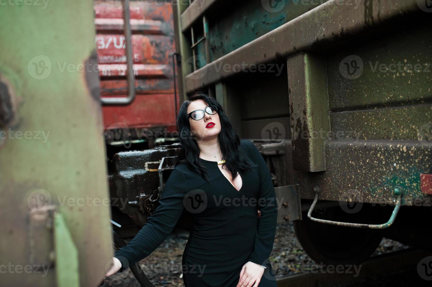 chica morena vestida de negro con gafas en la estación de tren. foto