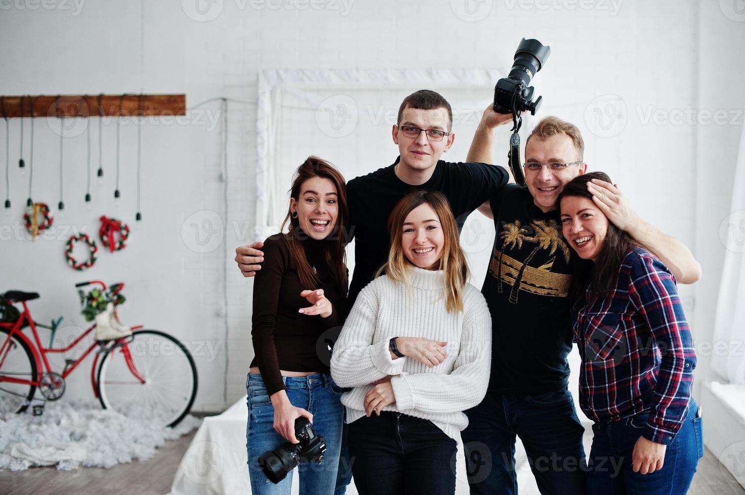 Group of five peoples, friends photographers and designers on studio shooting after hard work day. They happy and laughing. photo