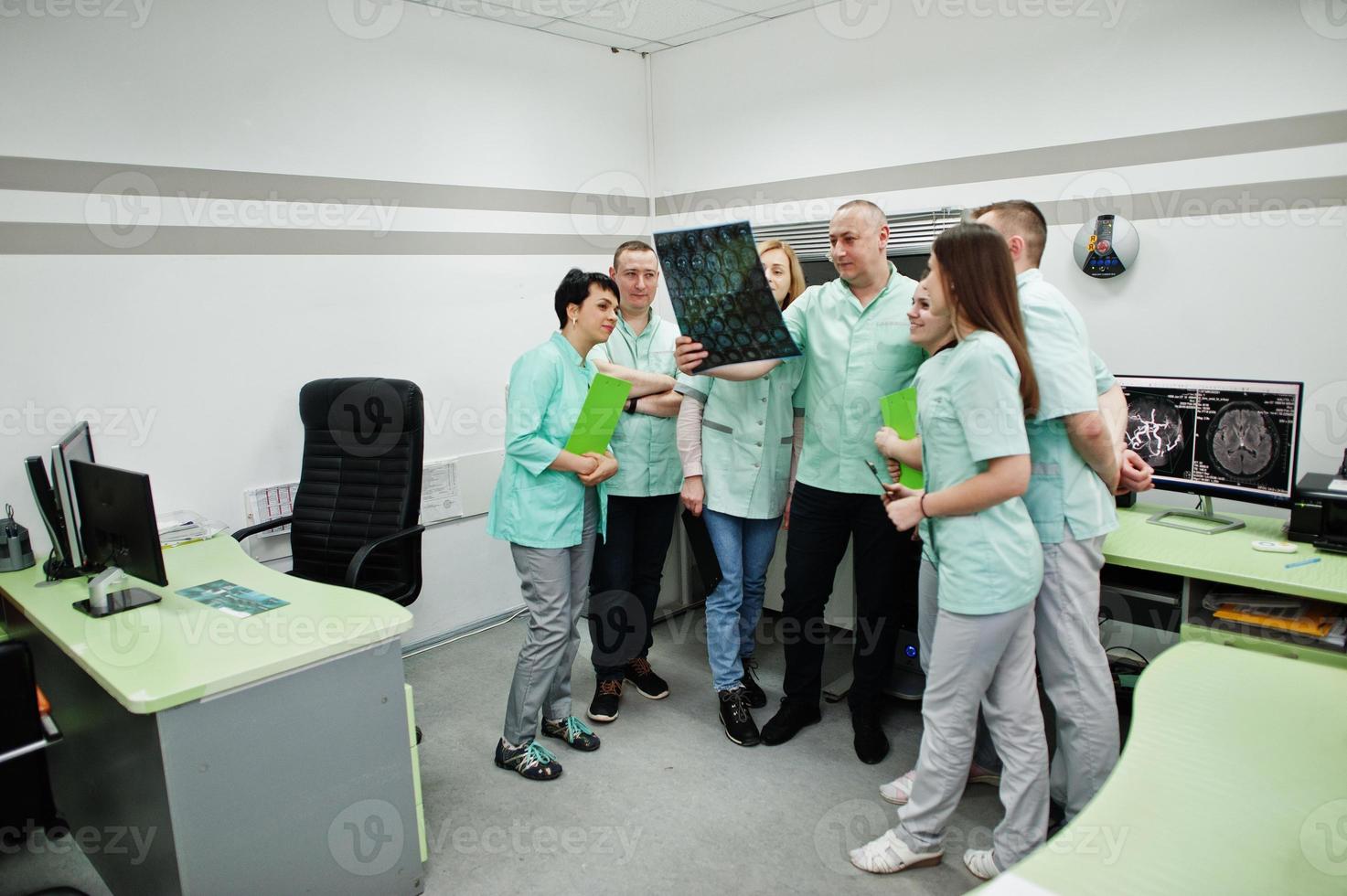 Medical theme.Observation room with a computer tomograph. The group of doctors meeting in the mri office and looking at x-ray at diagnostic center in hospital. photo
