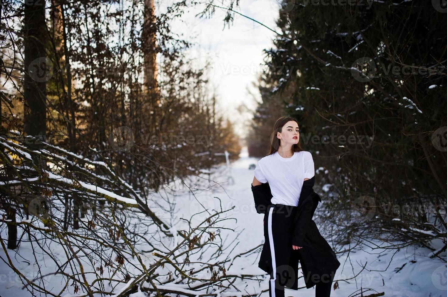 Fashionable long legs brunette model in long black cloak posed outdoor at winter day. photo