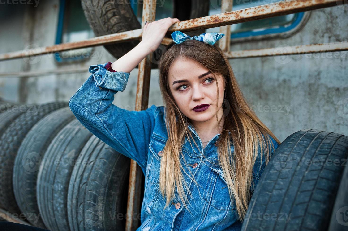 Young hipster girl in jeans jacket and head scarf at tire fitting zone. photo