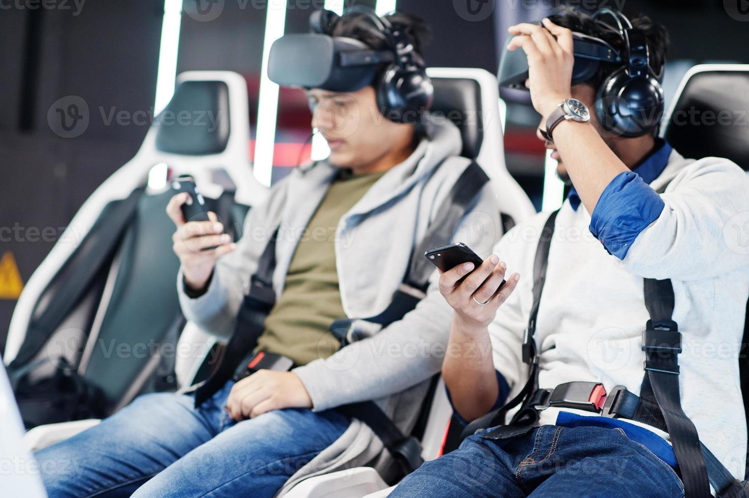 Two young indian people having fun with a new technology of a vr headset at virtual reality simulator with mobile phone at hands. photo