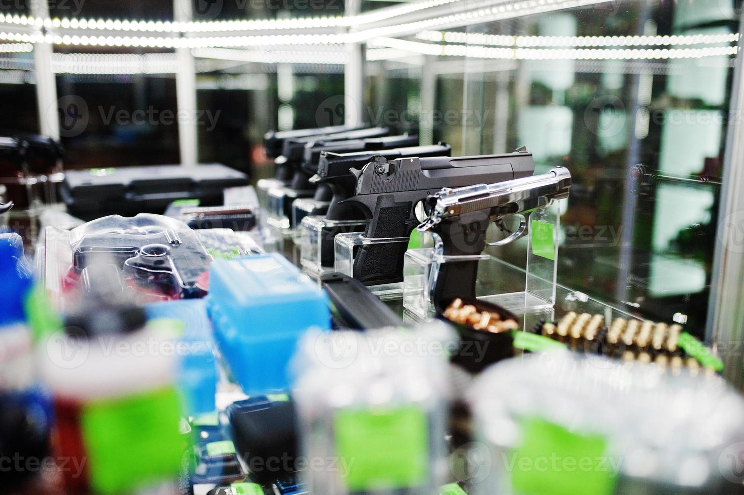 Different guns and revolvers on shelves store weapons on shop center. photo