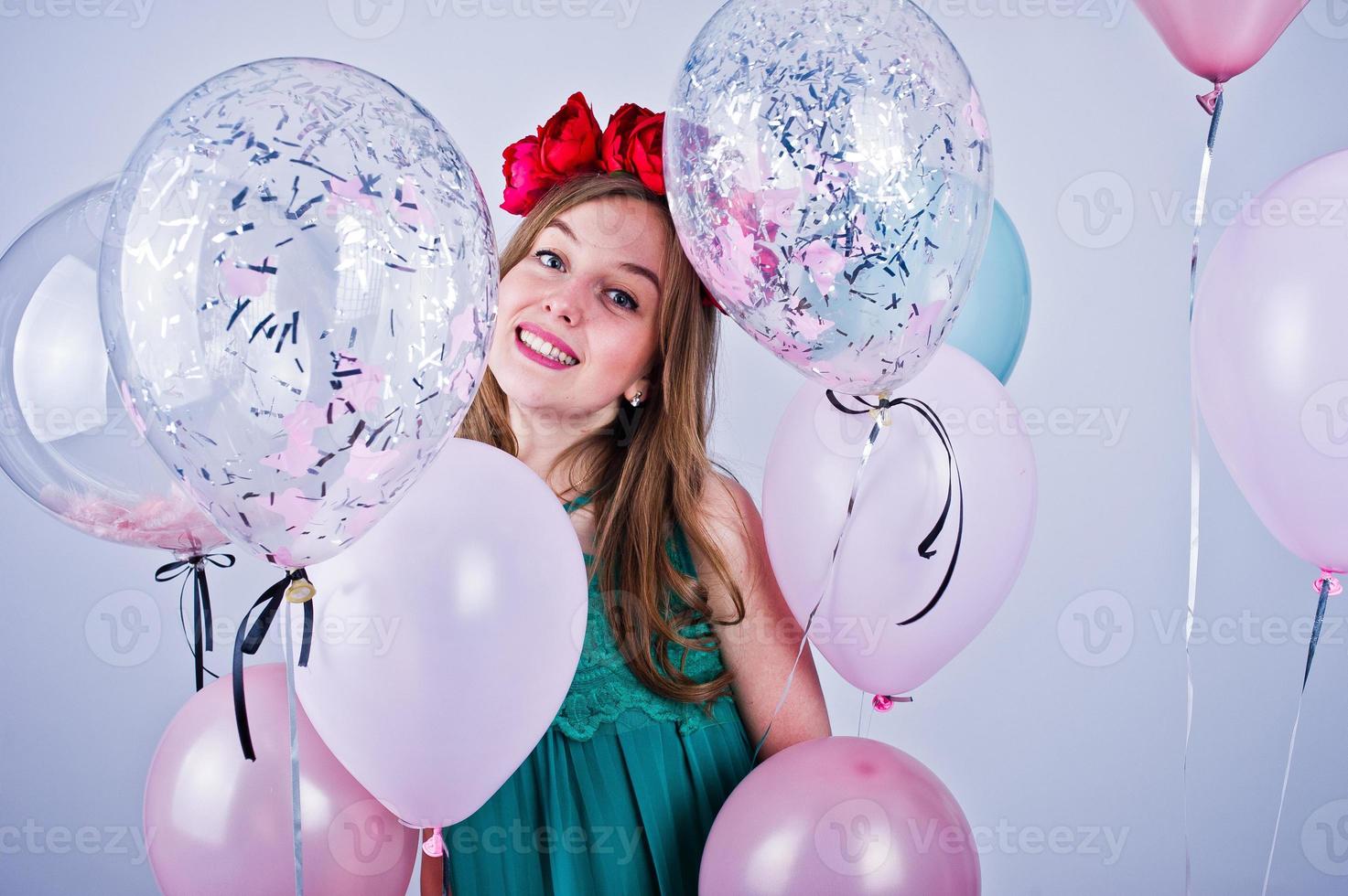 chica feliz con vestido verde turquesa y corona con globos de colores aislados en blanco. celebrando el tema del cumpleaños. foto