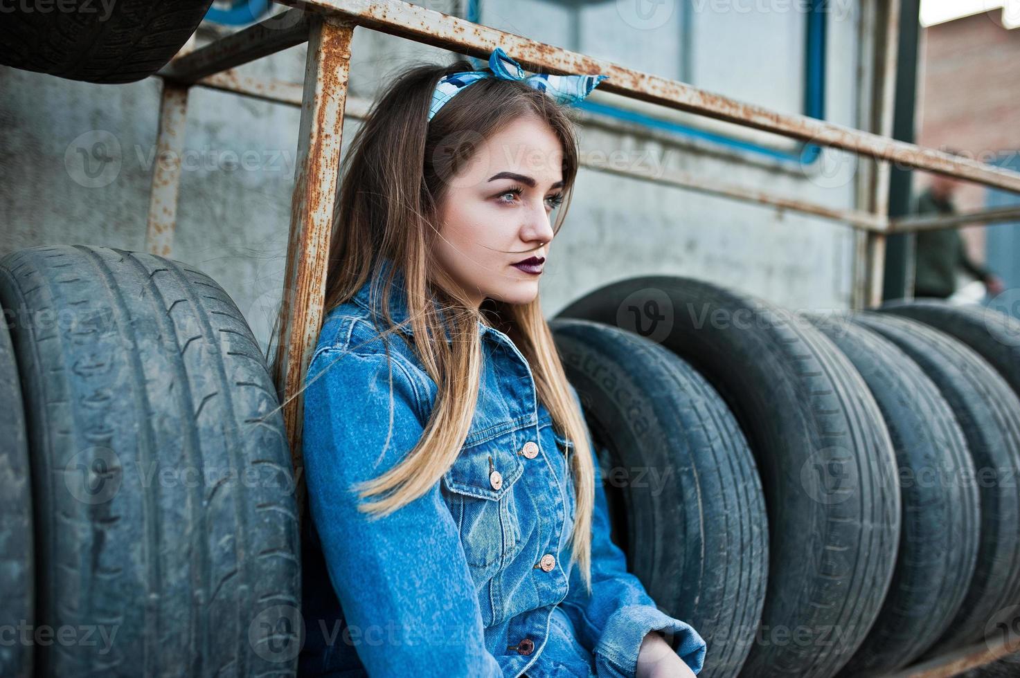 Young hipster girl in jeans jacket and head scarf at tire fitting zone. photo