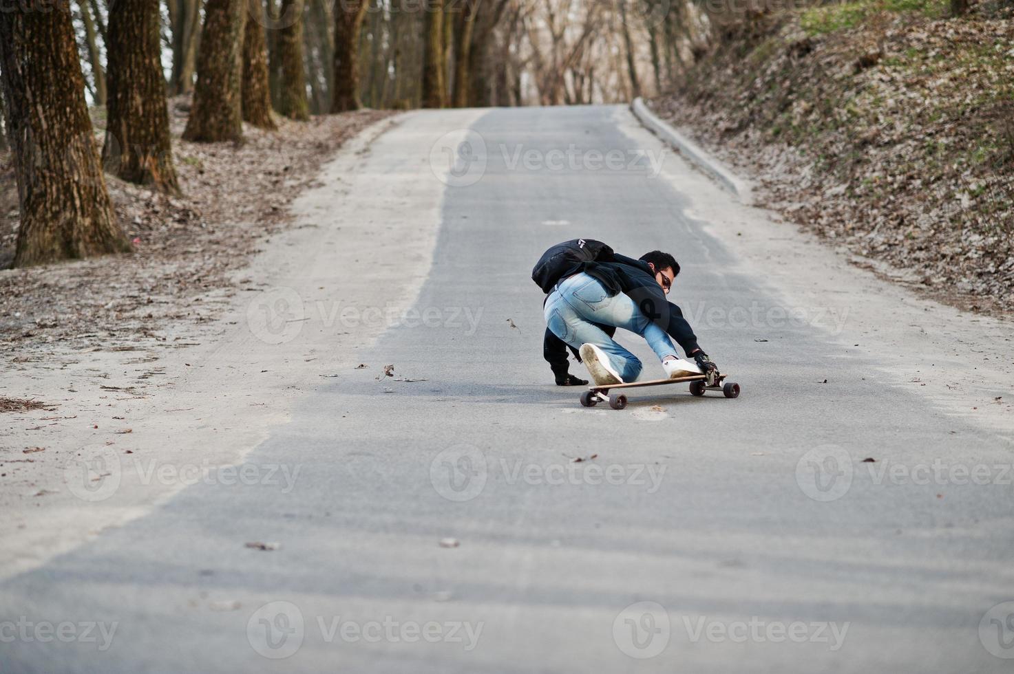 Fail falling from a skateboard. Street style arab man in eyeglasses with longboard longboarding down the road. photo