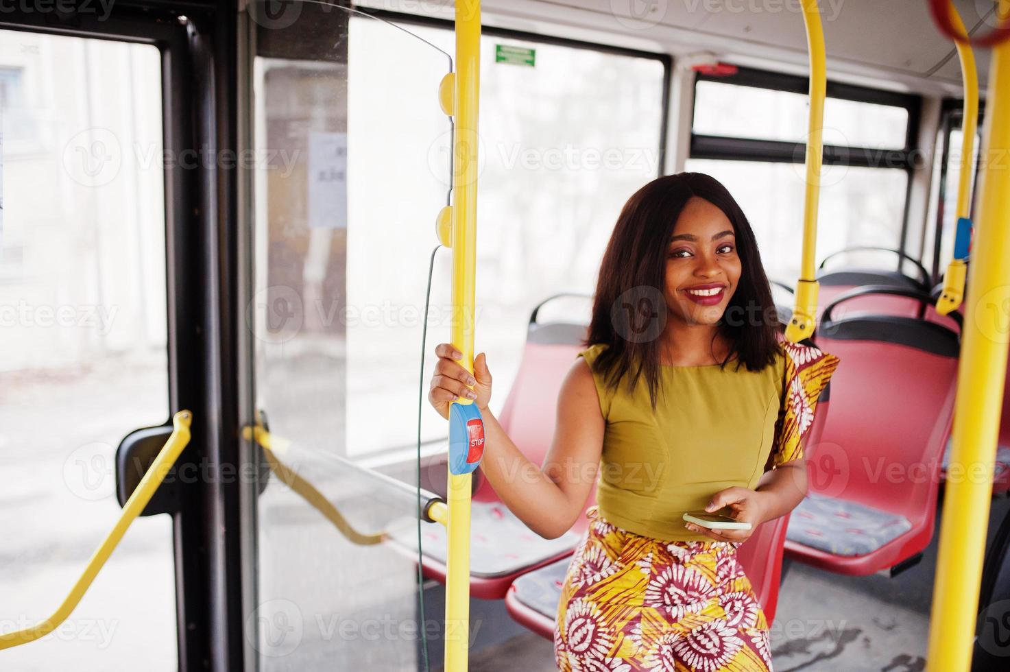 Young stylish african american woman riding on a bus with mobile phone. photo