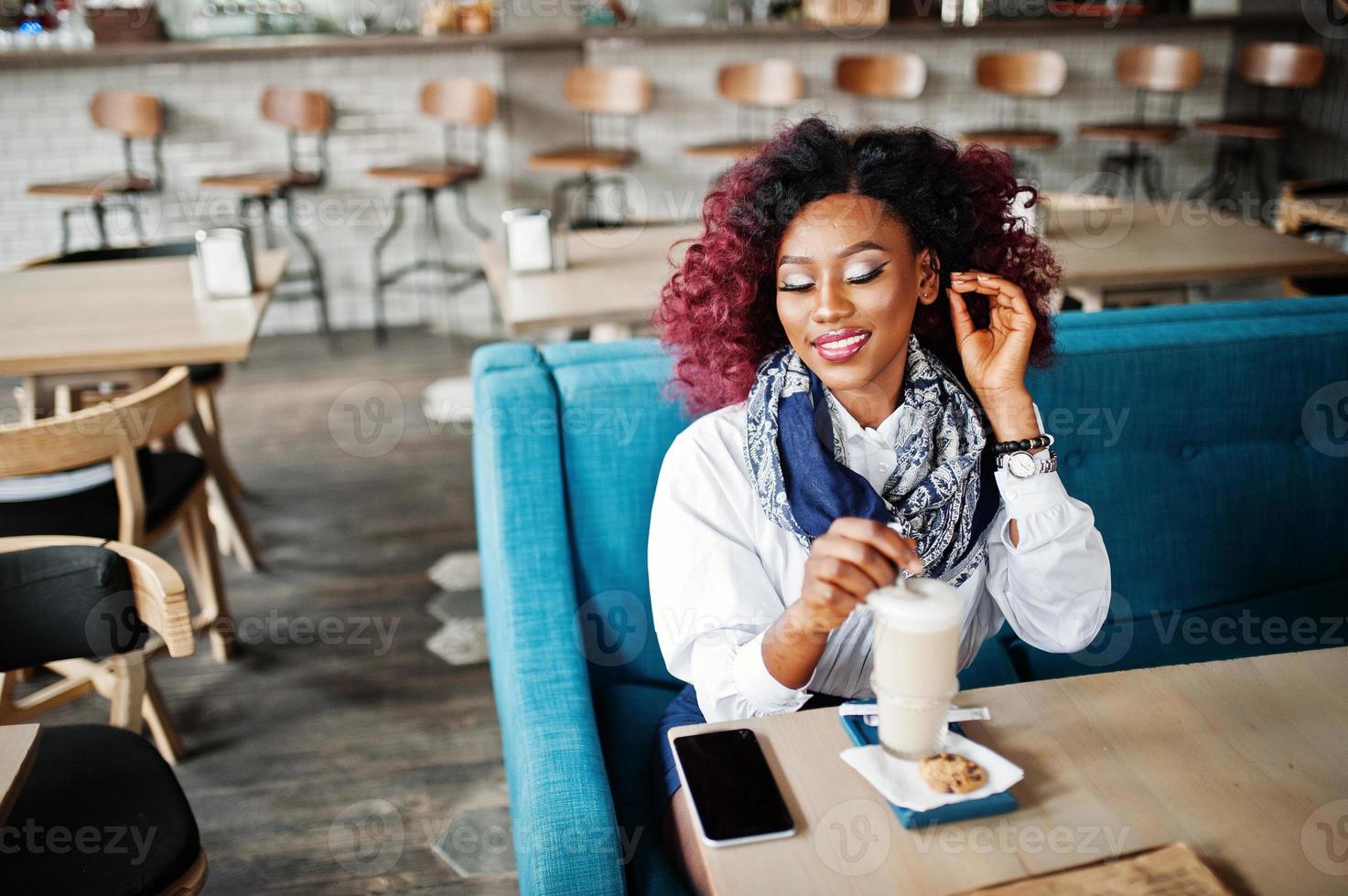 Attractive african american curly girl sitting at cafe with latte. photo