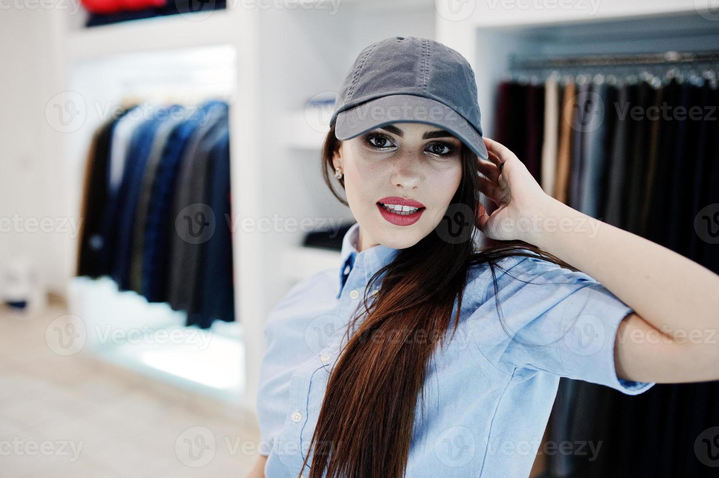 hermosa chica morena en la boutique de la tienda de ropa en ropa casual y gorra. foto