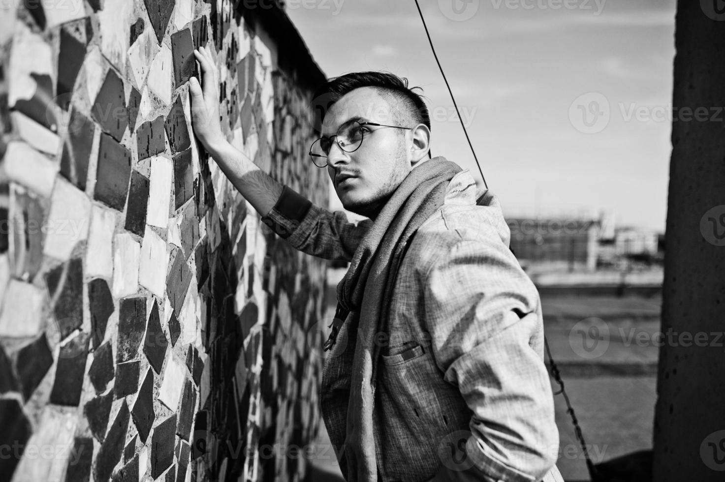 Dreamer stylish macho man in gray suit, scarf and glasses posed on the roof. photo