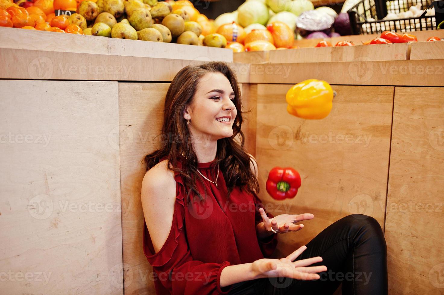 Girl in red throw peppers on fruits store. photo