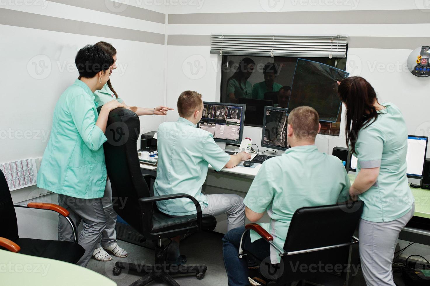 Medical theme.Observation room with a computer tomograph. The group of doctors meeting in the mri office at diagnostic center in hospital. Hold x-ray radiographic image. photo