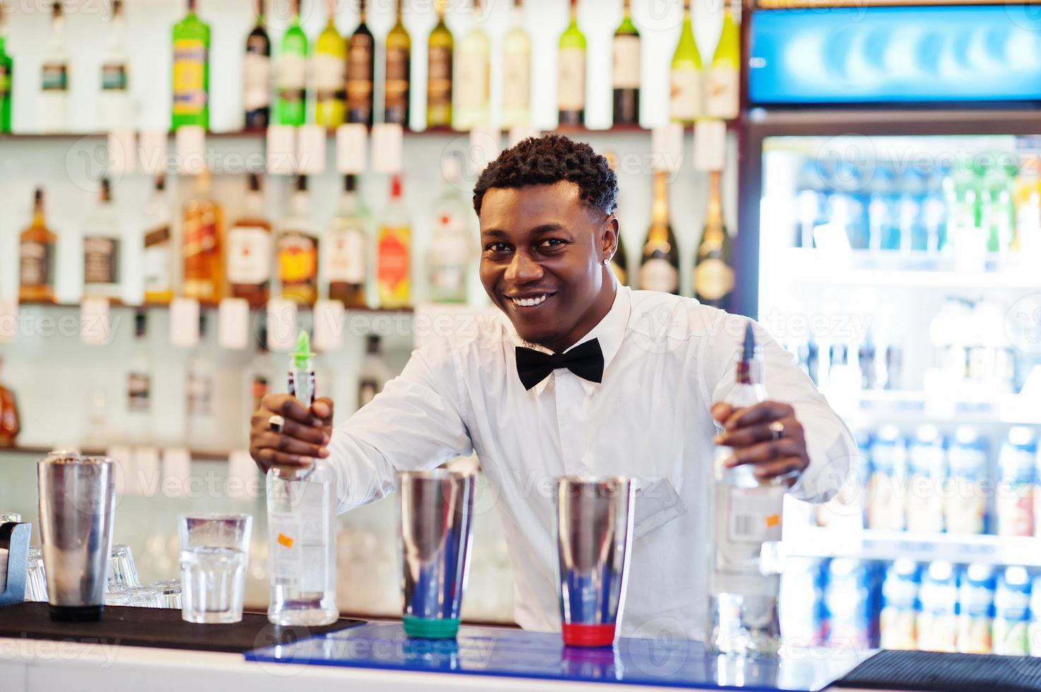 camarero afroamericano trabajando detrás del bar de cócteles. preparación de bebidas alcohólicas. foto