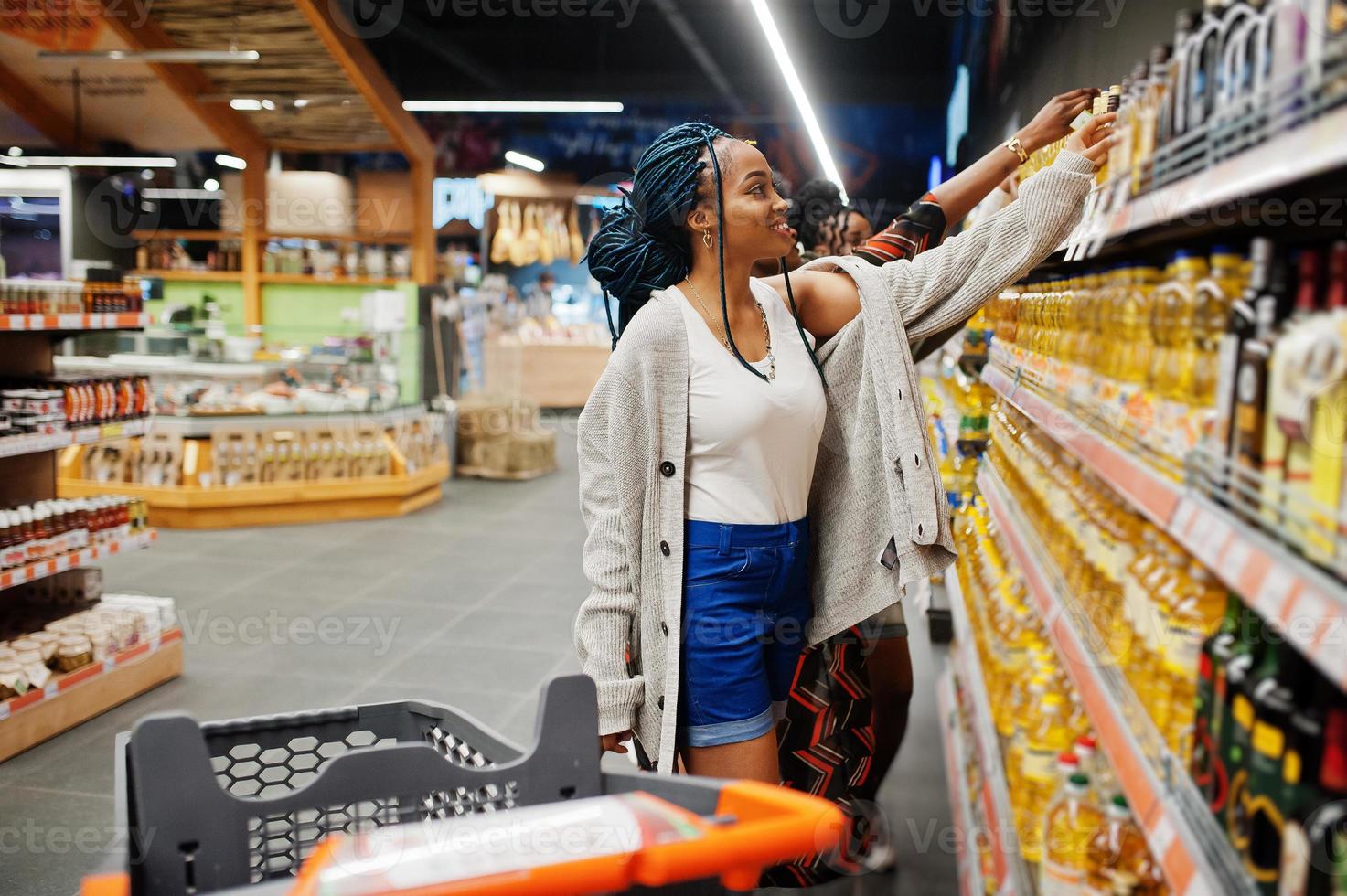 grupo de mujeres africanas comprando botellas de aceite de girasol en el supermercado. foto