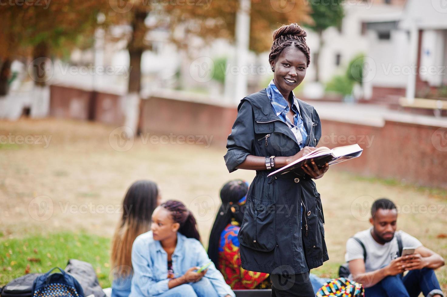 grupo de cinco estudiantes universitarios africanos que pasan tiempo juntos en el campus en el patio de la universidad. amigos negros afro estudiando. tema de la educación foto