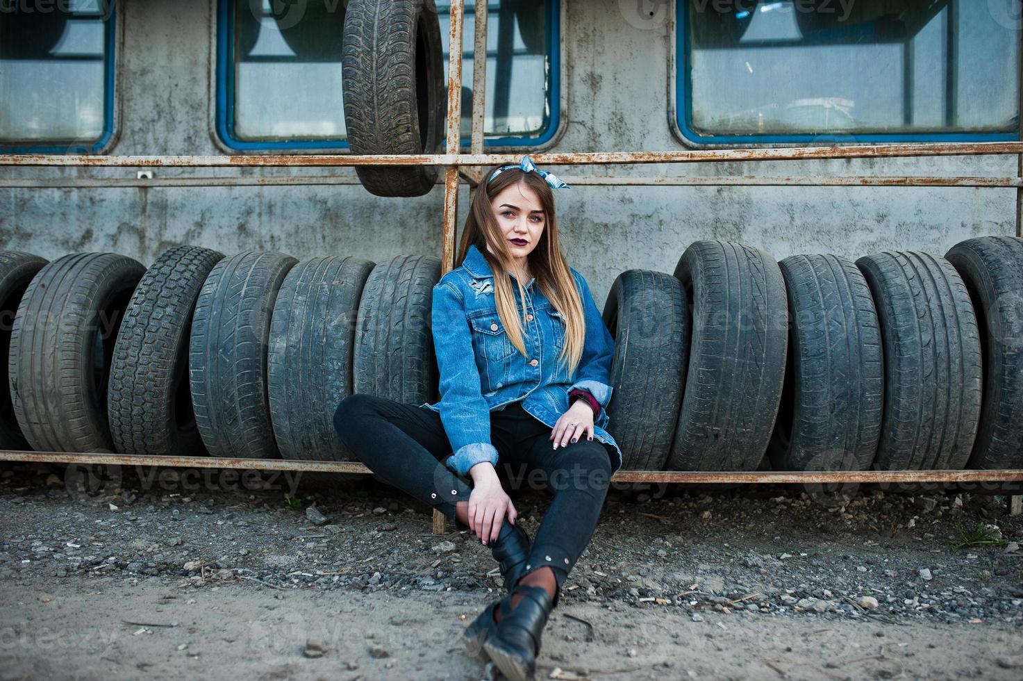 Young hipster girl in jeans jacket and head scarf at tire fitting zone. photo