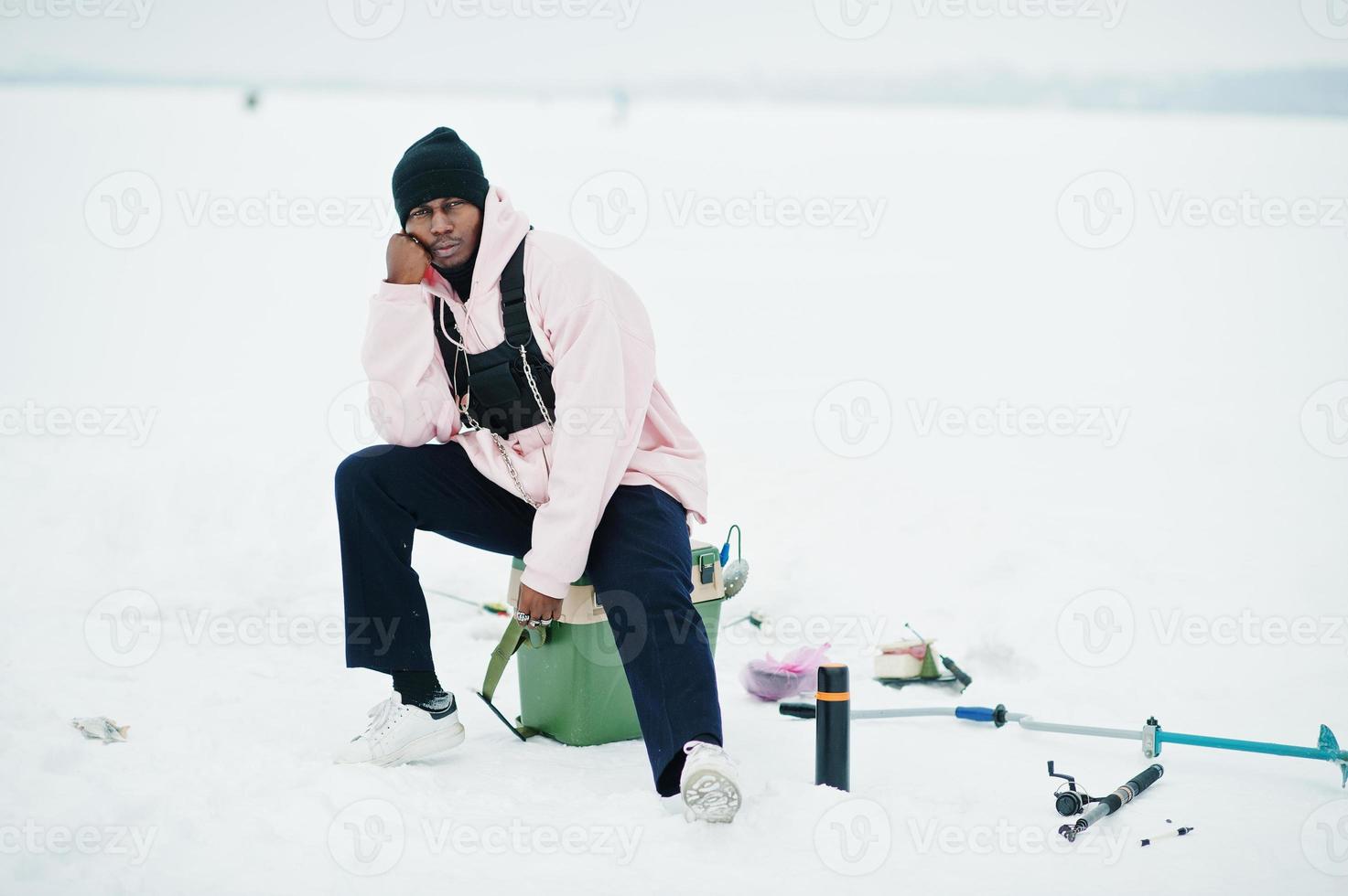 African american fisherman on frozen sea. Winter fishing. photo