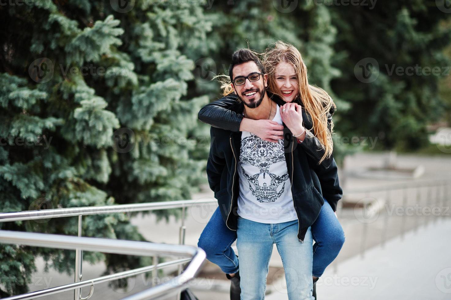 Cool multiracial couple posing. European girl jumped over shoulder arabian man. photo
