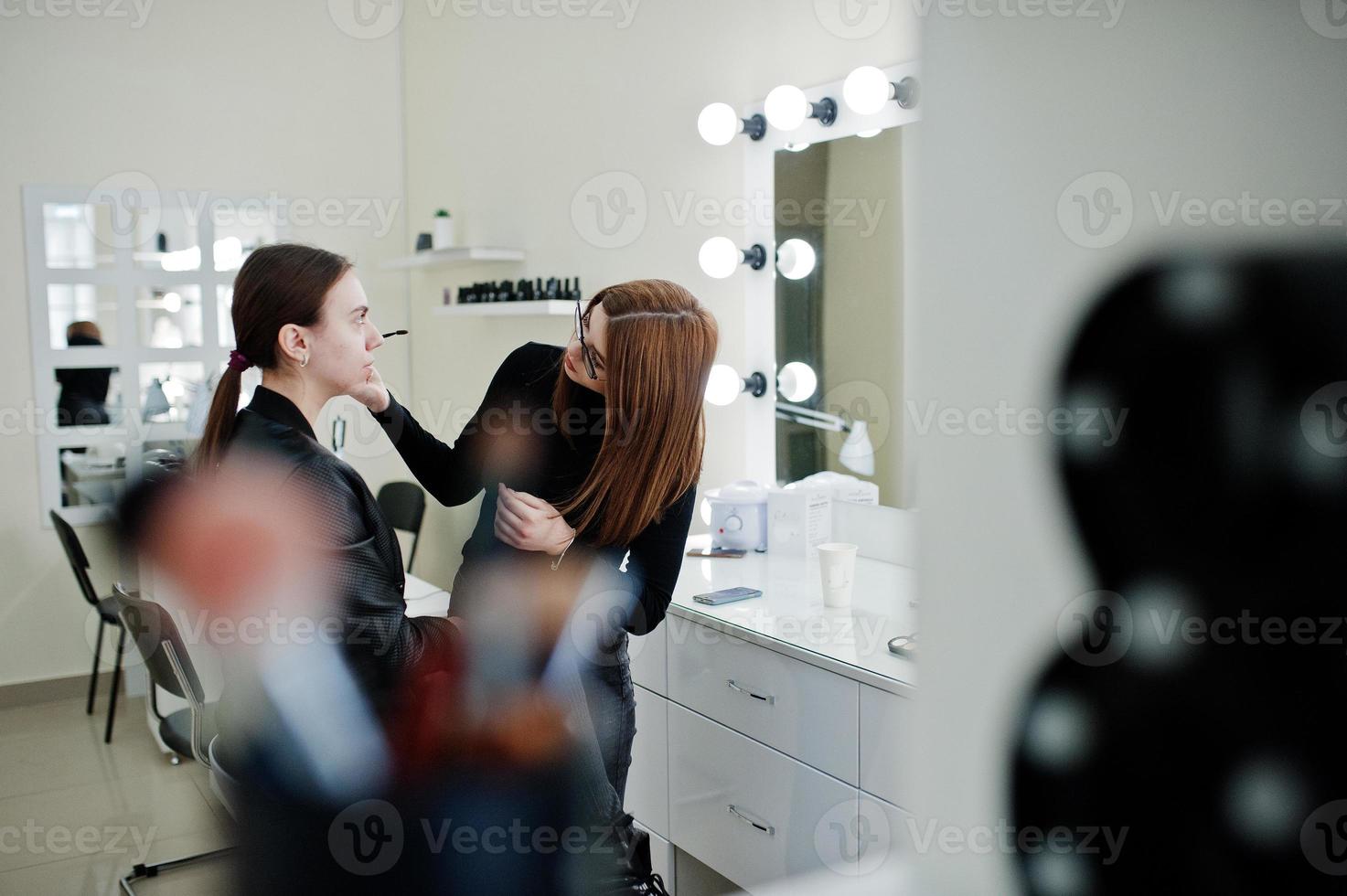 Make up artist work in her beauty visage studio salon. Woman applying by professional make up master. Beauty club concept. photo