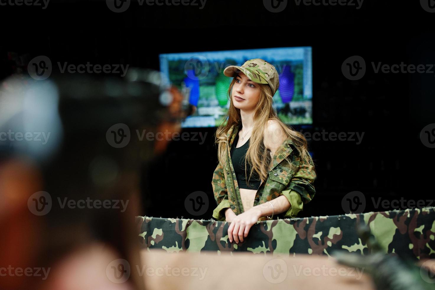 Military girl in camouflage uniform against army background on shooting range. Aim people. photo