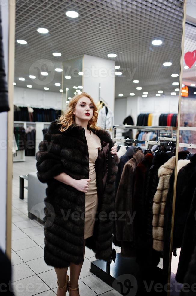 chica rubia de elegancia en abrigo de piel en la tienda de abrigos de piel y chaquetas de cuero. foto