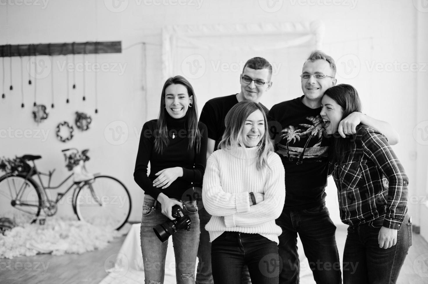 Group of five peoples, friends photographers and designers on studio shooting after hard work day. They happy and laughing. photo