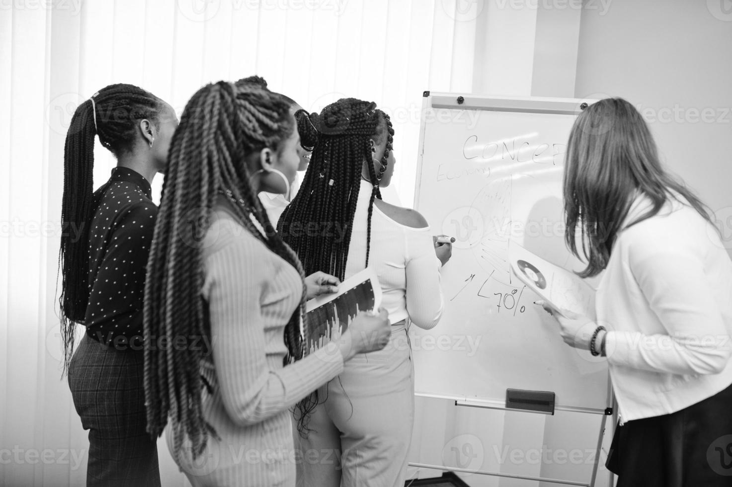 Multiracial women colleagues, crew of divercity female partners in office standing near flipchart. photo