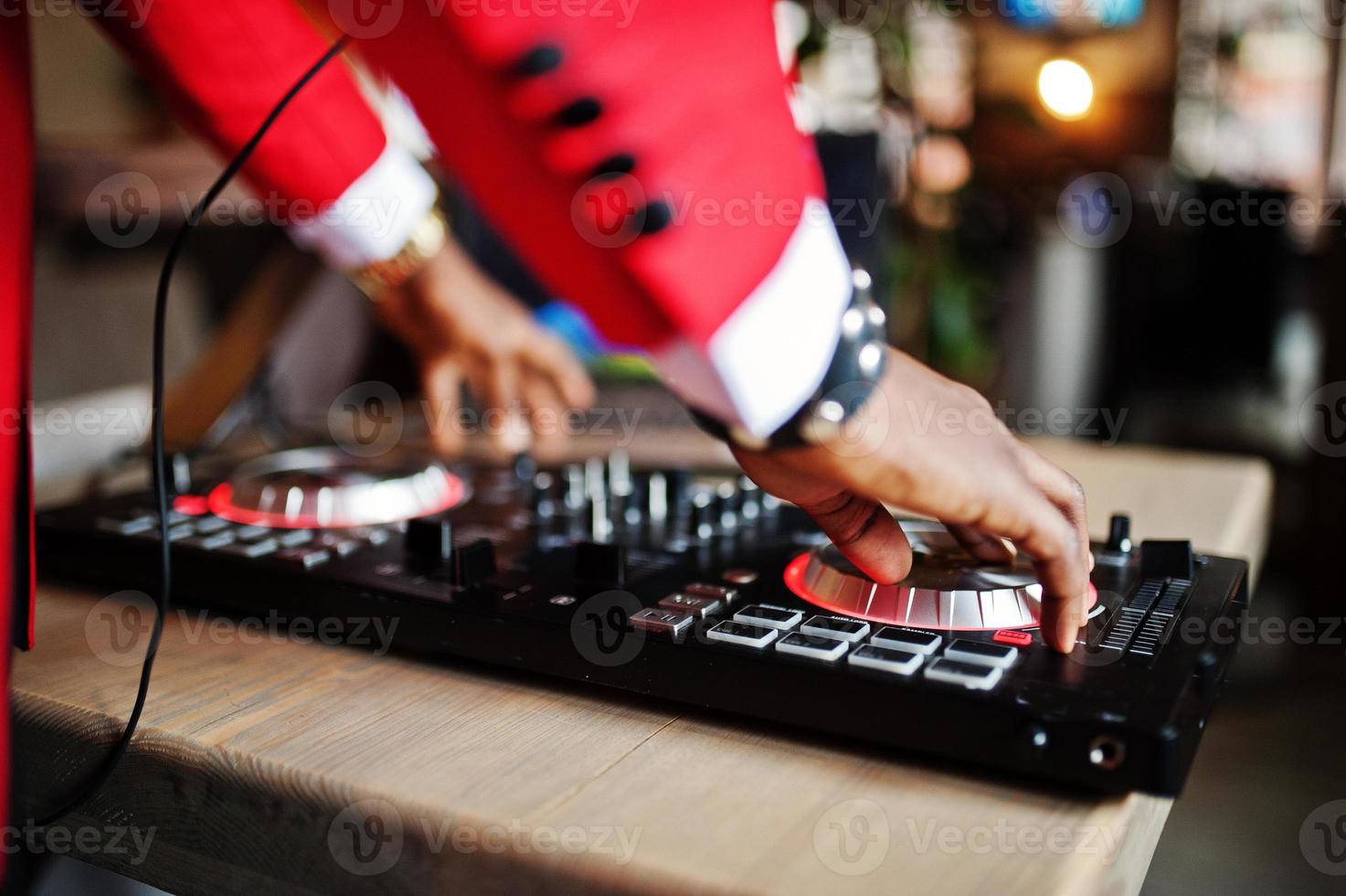 manos de moda hombre afroamericano modelo dj en traje rojo con controlador de dj. foto