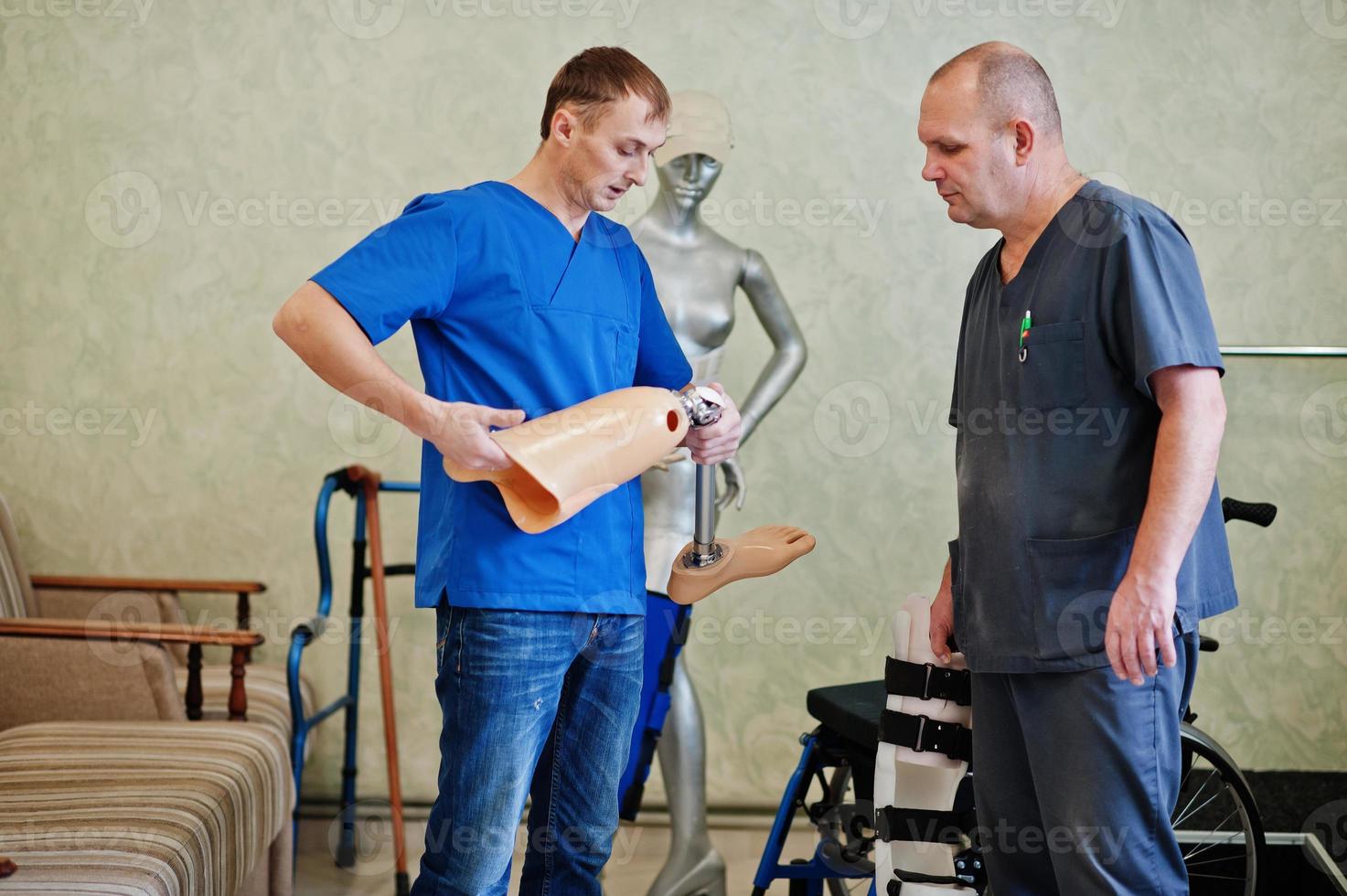 Two prosthetist man workers with prosthetic leg working in laboratory. photo