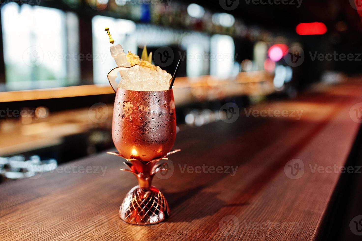 Alcoholic cocktail with ice in bronze glass on bar table. photo