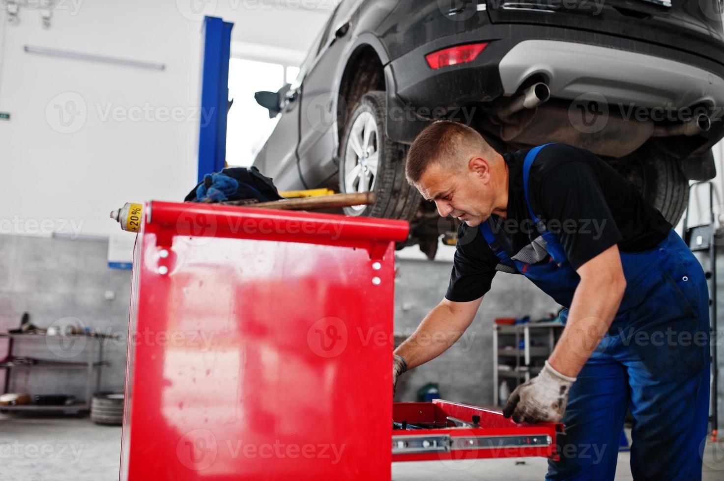 tema de reparación y mantenimiento de automóviles. mecánico en uniforme que trabaja en el servicio de automóviles. foto