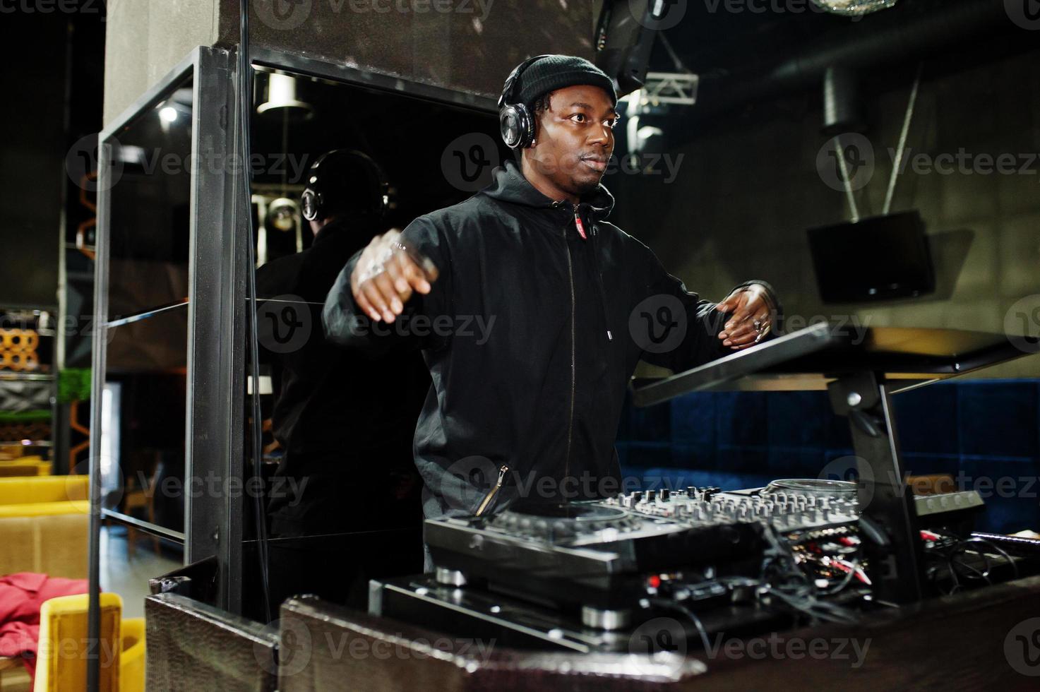 African american dj play music on decks at night club. photo