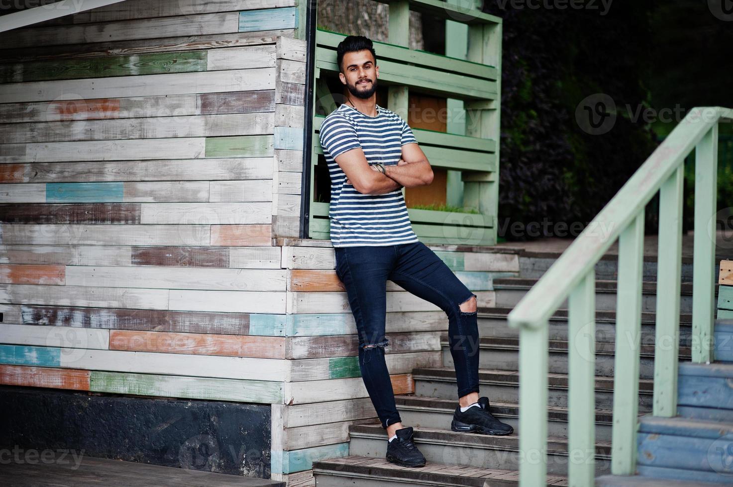 Handsome tall arabian beard man model at stripped shirt posed outdoor. Fashionable arab guy. photo