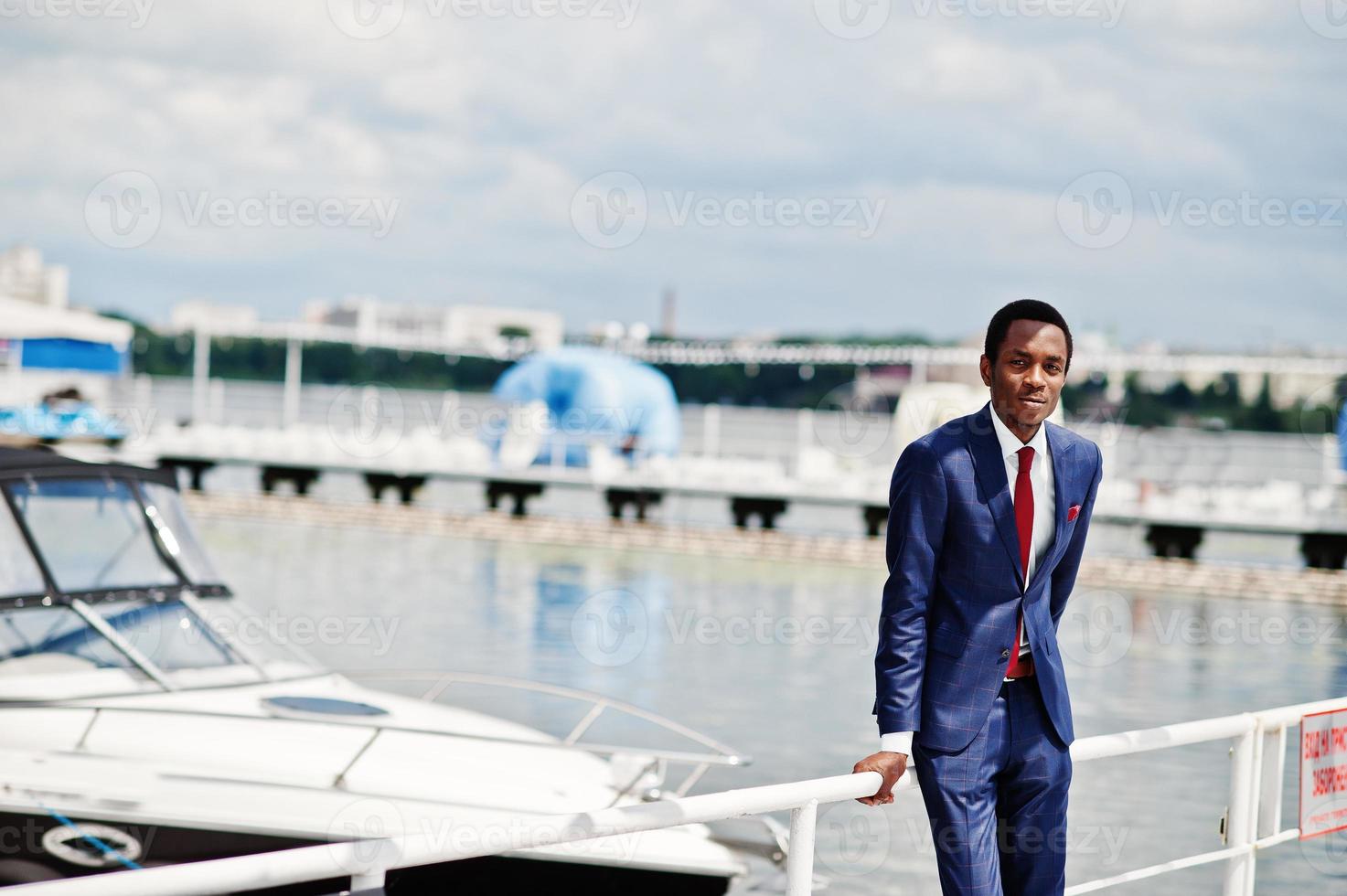 African american happy successful man at suit against yacht. Rich black business man. photo