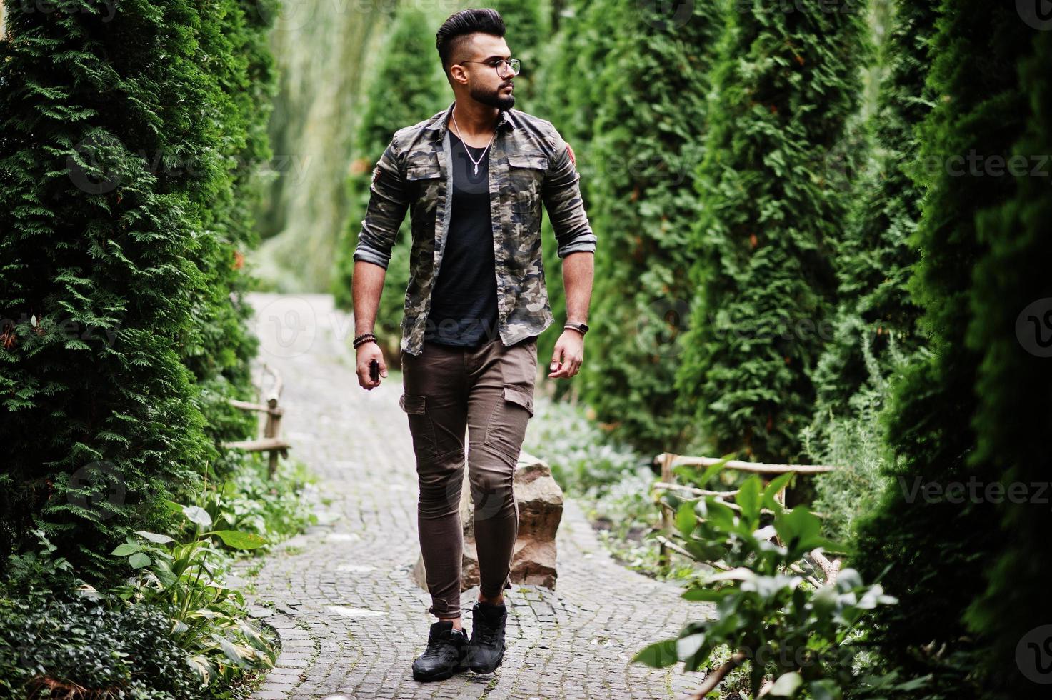 Awesome beautiful tall ararbian beard macho man in glasses and military jacket posed outdoor. photo